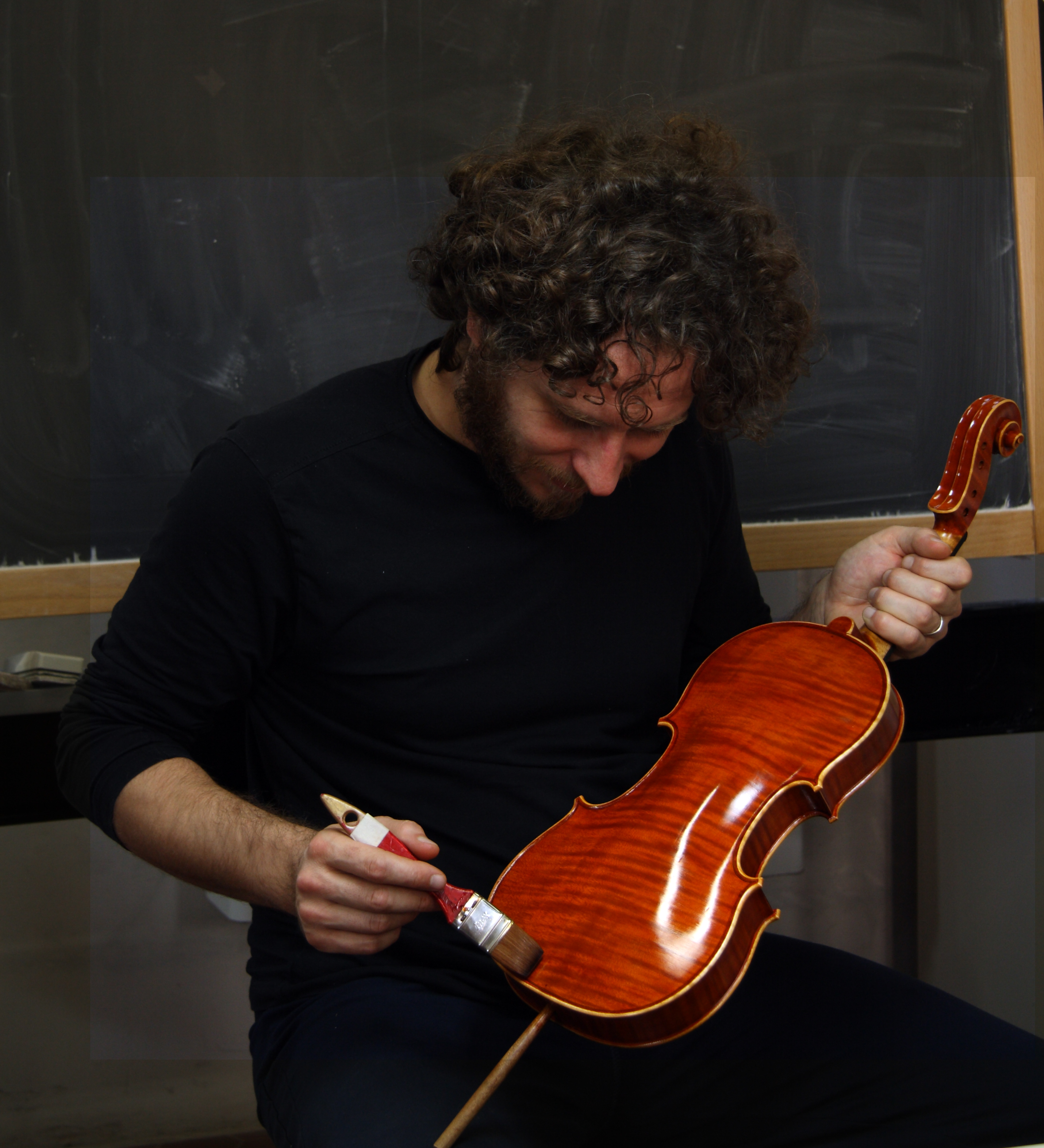 Student applying varnish to a violin